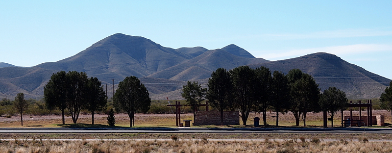 [Obvious non-native trees shading picnic areas while magestic-looking dark-rocked hills provide a backdrop.]